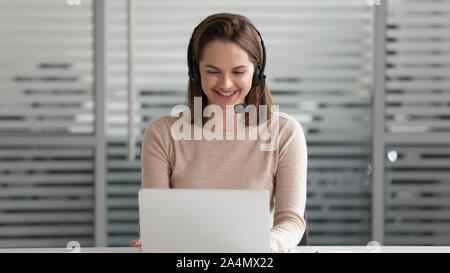 Smiling businesswoman in laptop casque, parler, travailler en ligne Banque D'Images