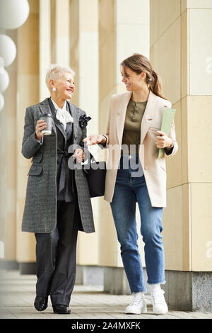 Deux professionnels des femmes dans des vêtements élégants parler et rire en se promenant dans la rue en plein air Banque D'Images