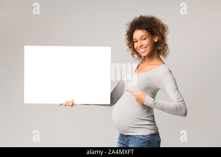 Happy afro femme enceinte à vide feuille de pointage de la publicité Banque D'Images