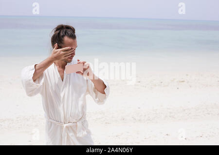 Homme portant une robe de chambre sur la plage Banque D'Images