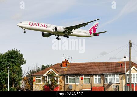 Un Boeing 777-300 de Qatar Airways jet volant à basse altitude au-dessus des toits à Hatton Cross sur son approche à l'atterrissage à Heathrow London England UK Banque D'Images