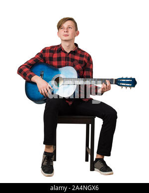 Portrait de l'adolescent garçon talentueux à jouer sur la guitare acoustique assis sur une chaise isolée sur fond blanc. Beaucoup de leçons de musique fo Banque D'Images