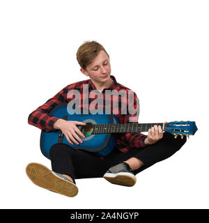 Portrait de l'adolescent garçon talentueux à jouer sur la guitare acoustique assis sur le plancher isolé sur fond blanc. Beaucoup de leçons de musique f Banque D'Images