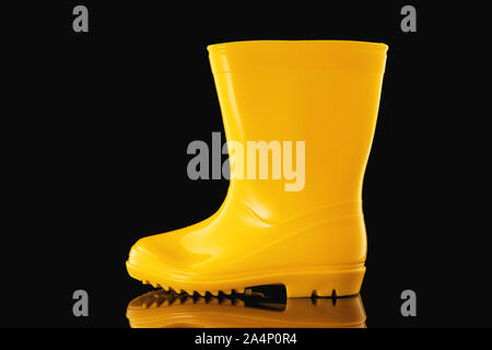 Bottes de pluie en caoutchouc jaune pour les enfants isolés sur fond noir Banque D'Images