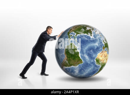 Side view of young businessman rolling la terre isolé sur fond blanc Banque D'Images