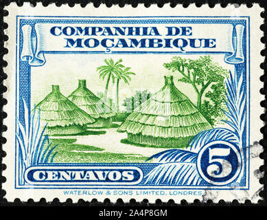 Huttes tribales sur vintage stamp du Mozambique Banque D'Images