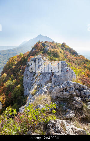 Pointues et un pic lointain rocky mountain chemin couvert d'arbres et arbustes avec des couleurs de l'automne, des feuilles Banque D'Images