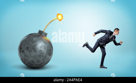 Un petit homme sur fond bleu courir loin de une bombe géante avec un fusible allumé. Banque D'Images