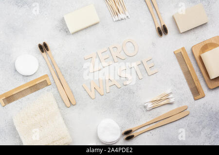 Zéro déchets avec accessoires naturel biodégradable. Brosses à dents en bambou à la main, savon sans emballage pains shampooings, coton-tiges, luffa sur le béton blanc en dessus de table, vue de dessus, selective focus Banque D'Images