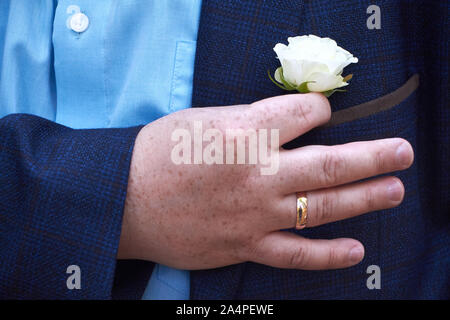 Gros plan d'une boutonnière rose blanche dans une poche d'un veston bleu, selective focus Banque D'Images
