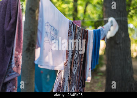 Le linge est séché à l'extérieur sur une corde à linge. Accrocher les choses colorées et sec dans la nature. Banque D'Images