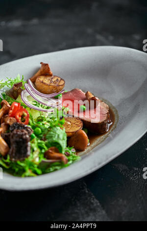 Tagliata de boeuf avec légumes. Close-up, clé faible, fond gris Banque D'Images