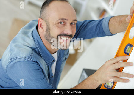 Portrait de l'homme marquant sur le mur avec niveau Banque D'Images