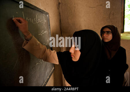 Un élève écrit sur un tableau noir, à l'école communautaire (CBS) dans une mosquée, à Qala-e- Haji Yahya village, dans Anjil district de la Province d'Herat, Afghanistan. Un nombre total de 395 enfants fréquentent cette communauté informelle sur l'école primaire de trois classes de la première à la troisième année. Il y a cinq enseignants pour les trois classes. L'Afghanistan. Le 7 mai 2009. Banque D'Images