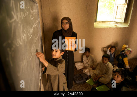 Un garçon écrit sur un tableau noir, à l'école communautaire (CBS) dans une mosquée, à Qala-e- Haji Yahya village, dans Anjil district de la Province d'Herat, Afghanistan. Un nombre total de 395 enfants fréquentent cette communauté informelle sur l'école primaire de trois classes de la première à la troisième année. Il y a cinq enseignants pour les trois classes. L'Afghanistan. Le 7 mai 2009 Banque D'Images