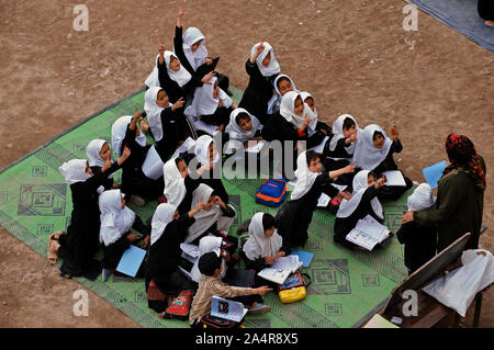 Les enfants fréquentent une classe en plein air, à la course de gouvernement Pul-e-Rangeena l'école primaire pour les filles, dans le nord-ouest de la ville de Herat, Afghanistan. Le 6 mai 2009. Comme beaucoup d'autres écoles en Afghanistan cette école a également été surpeuplées et retour des enfants après plusieurs années de conflit. Autour de 9000 enfants fréquentent cette école en trois équipes de sorte qu'il est difficile pour la direction de l'école pour accueillir tous les enfants dans une bonne classe. Le bâtiment principal dispose de seulement 20 salles de classe et même après la mise en place de 43 tentes dans les locaux scolaires, des centaines d'enfants ont à assister à des cours à l'ouvrir. Banque D'Images