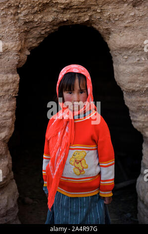 Une jeune fille se dresse à l'entrée d'une grotte où sa famille à garder le bétail pour les garder au chaud près de sa maison, dans le village de Rag-e-Shad, à la périphérie de la ville de Bamyan, dans le centre de la province de Bamyan, en Afghanistan. Le 11 mai 2009. Banque D'Images