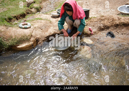 Une jeune fille lave la vaisselle dans un cours d'eau naturel, dans le village d'Surkhjoi Fuladi, vallée, dans la province de Bamyan, en Afghanistan. Le 11 mai 2009. Banque D'Images