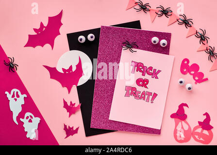 Créations en papier créatif Halloween télévision réside dans rouge foncé et noir. Vue de dessus avec les chauves-souris, fantômes, citrouilles, yeux chocolat, texte 'trick or treat' sur une carte Banque D'Images