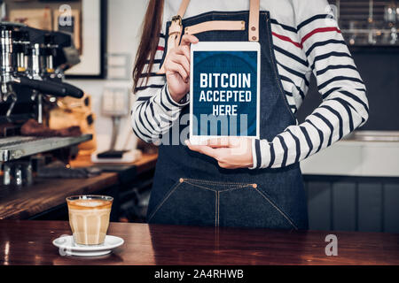 Close up woman holding tablet barista et montrer acceptés ici bitcoin sur écran de tablette au café bar comptoir café,le vendeur accepte le paiement par crypto Banque D'Images