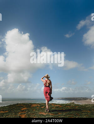 Windy Beach Day - femme blonde en robe rouge - Fleurs de soleil Banque D'Images