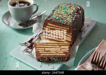Gâteau moelleux au chocolat avec des biscuits et d'écimage, servi sur le plateau en céramique bleu et avec une tasse de café noir Banque D'Images