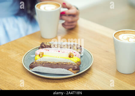 Les différents morceaux de gâteaux sucrés sur les plaques. Le petit-déjeuner dans le café. Sur fond de main de femme sont maintenant tasse de café. Banque D'Images