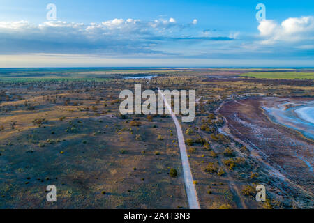 Route de gravier passant à travers le désert australien au lever du soleil - paysage aérien Banque D'Images