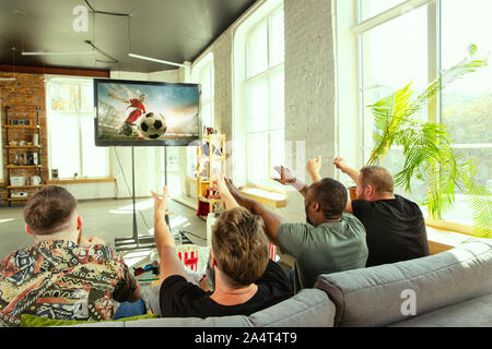 Groupe d'amis regarder match à la télé à la maison. Fans de sport passer du temps et avoir du plaisir ensemble. Expressif, émotionnel, jeu passionnant. Pour encourager l'équipe de soccer ou de football préférée, l'amitié, de semaine. Banque D'Images