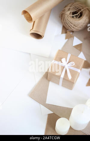 Enveloppés de vacances cadeau. Décorations de Noël et du Nouvel An de papier Kraft, ficelle, des bougies. Jours fériés au décor blanc et marron. Banque D'Images