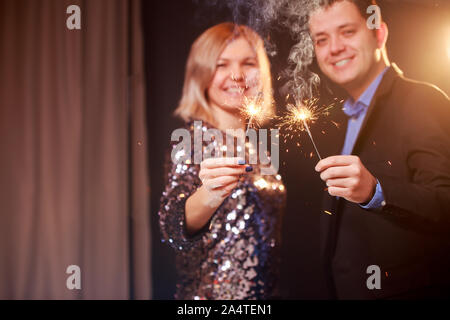 Photo de l'heureux couple avec cierges sur fond noir en studio Banque D'Images