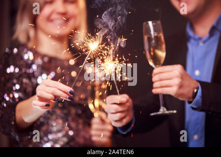 Photo de couple avec verres de champagne et cierges sur fond noir en studio Banque D'Images