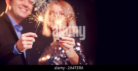 Photo de smiling couple avec cierges sur fond noir en studio Banque D'Images