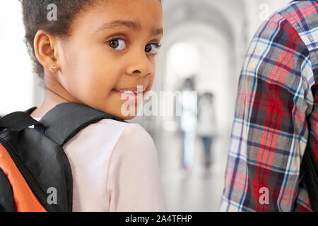 Close up of pretty brunette fille de l'école à la caméra à l'épaule au cours de la classe d'officier de leçon. Petite fille sur le corridor avec ses amis sur le temps de pause. Les enfants sur l'arrière-plan. Banque D'Images