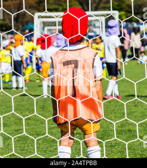 Un garçon comme un gardien ou gardien d'enfants en attente durant un match de football. Banque D'Images