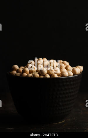 Les pois chiches dans un bol en céramique noire sur fond sombre Banque D'Images