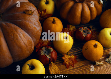 Un tas de citrouilles et pommes. Citrouilles d'automne aux pommes sur fond de bois et de feuilles. Citrouilles Orange sur une table en bois dans le jardin d'automne Banque D'Images