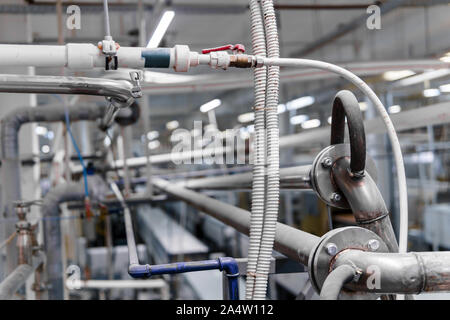 Différents câbles et pipelines dans un atelier industriel gros plan sur un arrière-plan flou Banque D'Images