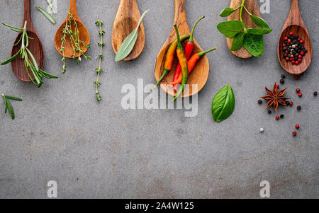 Divers des épices et fines herbes dans des cuillères en bois. Mise à plat ingrédients épices poivre, piment ,rosemarry, le thym, l'anis étoilé, feuilles de sauge et basilic Banque D'Images