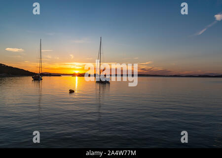 Colorés, côtières, Coucher de soleil à partir de la Sardaigne avec un Golden, Méditerranée tranquille & les îles de la Madallena et Caprera avec 2 bateaux amarrés, Banque D'Images