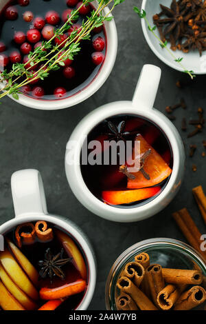 Vin chaud de Noël ou boire dans une tasse avec les agrumes orange,apple,des bâtons de cannelle et les étoiles d'anis sur fond de béton gris foncé close-up Banque D'Images