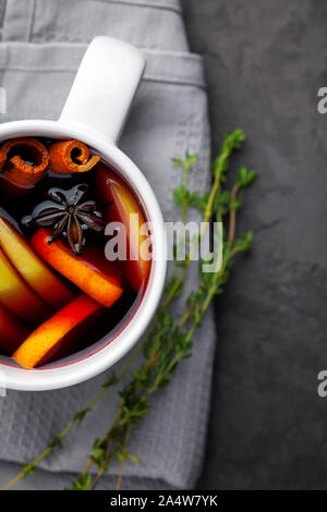 Vin chaud de Noël ou gluhwein boire dans une tasse avec les agrumes,apple,des bâtons de cannelle et anis sur fond de béton gris foncé top view copy space Banque D'Images