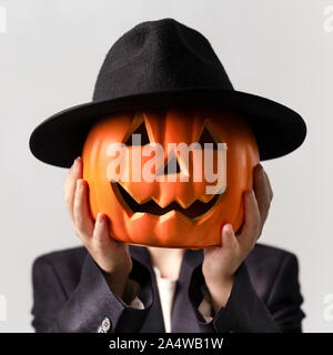 Man holding Jack o Lantern tête à chapeau noir sur son visage Banque D'Images