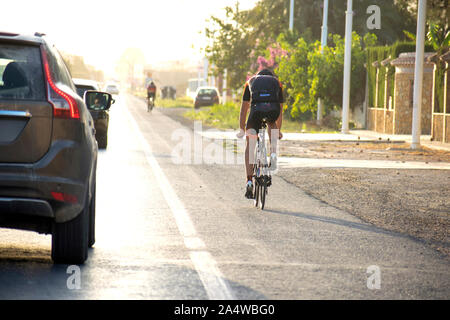 Murcia, Espagne, le 10 octobre 2019 : faire du vélo sur la route le long de voitures qui passent à côté de lui. L'homme monte un vélo sur la rue. Bicycle Rider en moto Banque D'Images