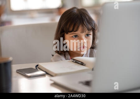 Petite fille regardant quelque chose sur l'ordinateur portable de sa mère Banque D'Images