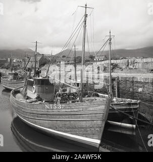 Années 1950, historiques, sur la côte d'Antrim, de vieux bateaux de pêche en bois amarré dans un port, N. 259 et N. 153, l'Irlande du Nord. Banque D'Images