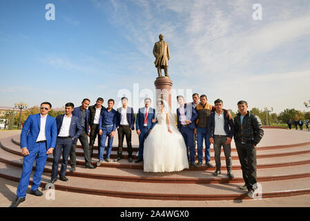 Une séance de photos pour le mariage en face de la statue du défunt chef Islam Karimov. Samarkand, Ouzbékistan Banque D'Images