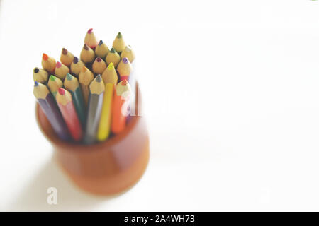 Crayons de couleur dans un pot en argile sur un bureau en bois blanc, dans une leçon d'art de la classe. Copie vide de l'espace pour le contenu de l'éditeur. Banque D'Images