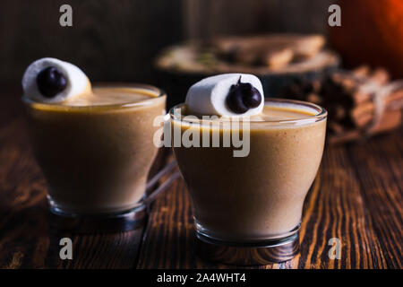 Happy monster, pumpkin spice latte de crème fouettée et de grands yeux de guimauve sur le dessus, d'Halloween, dessert de la guimauve sur smiley onglet rustique en bois Banque D'Images