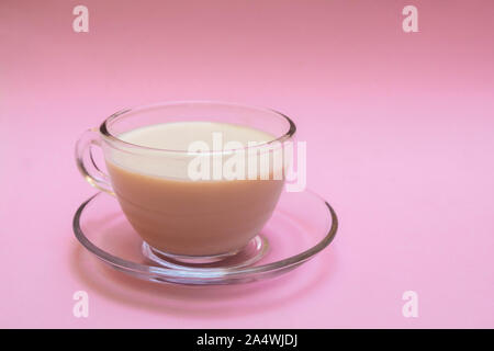 Lait indien masala chai (thé) dans une tasse en verre sur fond rose doux Banque D'Images